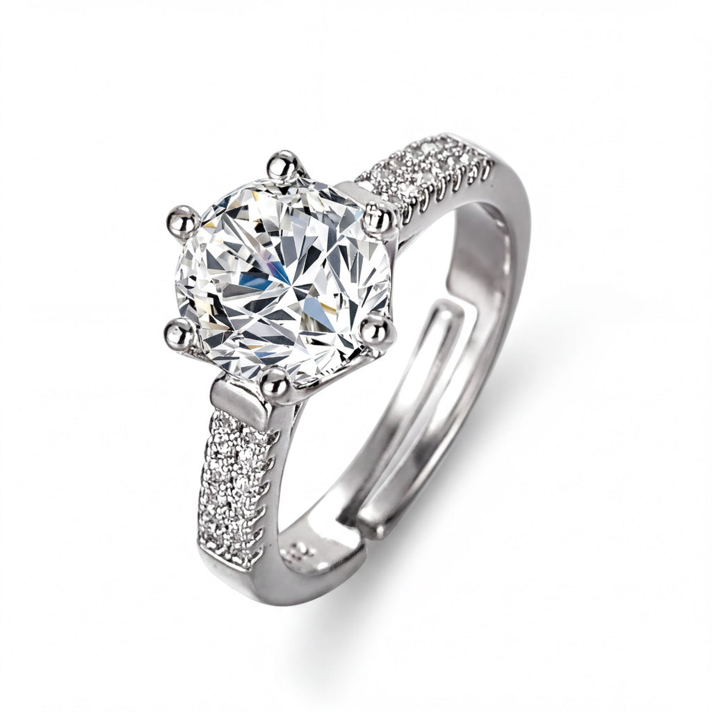 A silver ring with a large, clear gemstone set in the center, surrounded by smaller diamonds.