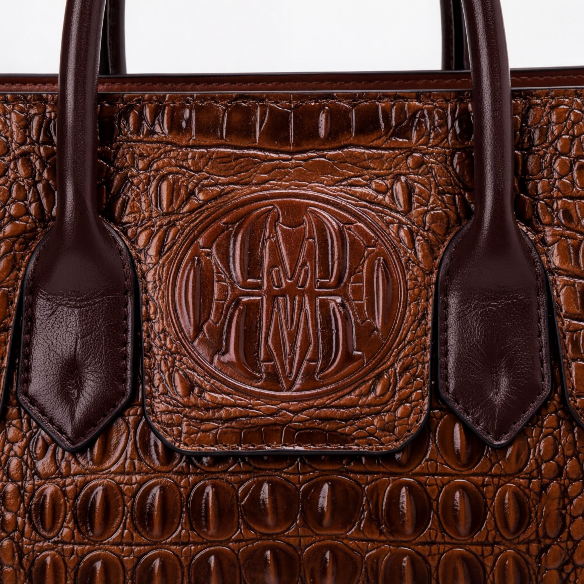 A close-up image of a brown leather handbag with a distinctive embossed logo on the front.