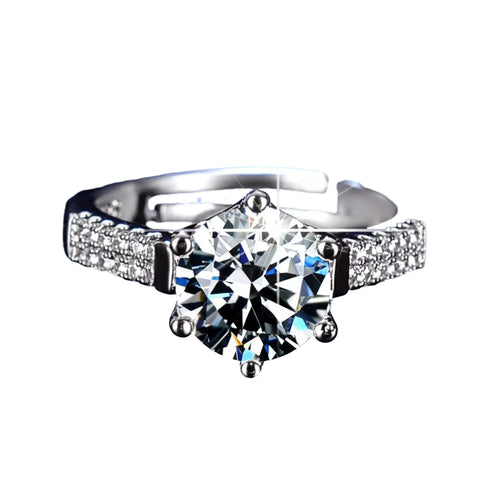 A close-up of a diamond engagement ring with a large central diamond surrounded by smaller diamonds on either side, set in a silver band.